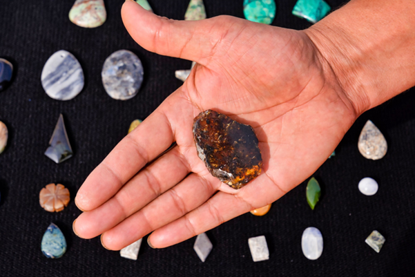 A person holding a dark amber-colored stone A person holding a dark amber-colored stone