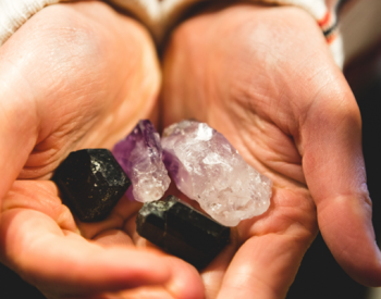 A variety of raw, authentic crystals including a dark tourmaline, amethyst point, and clear quartz