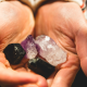A variety of raw, authentic crystals including a dark tourmaline, amethyst point, and clear quartz