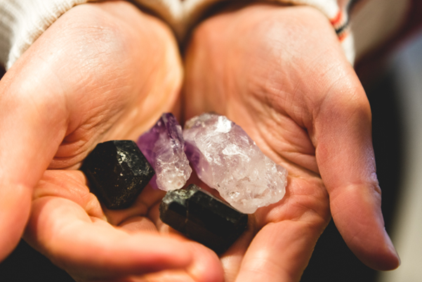A variety of raw, authentic crystals including a dark tourmaline, amethyst point, and clear quartz