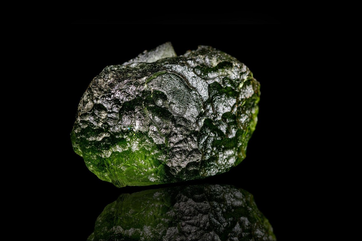 Macro view of authentic moldavite crystal highlighting natural texture and green color