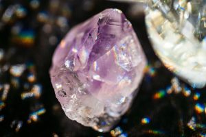 Macro photograph of an amethyst crystal specimen with purple colour depth and prismatic light reflections, illustrating colour tone and grade assessment criteria for bulk crystal buyers
