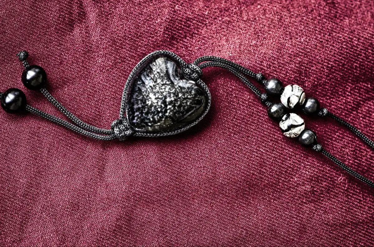 Heart-shaped meteorite pendant bracelet on red fabric with dark beads
