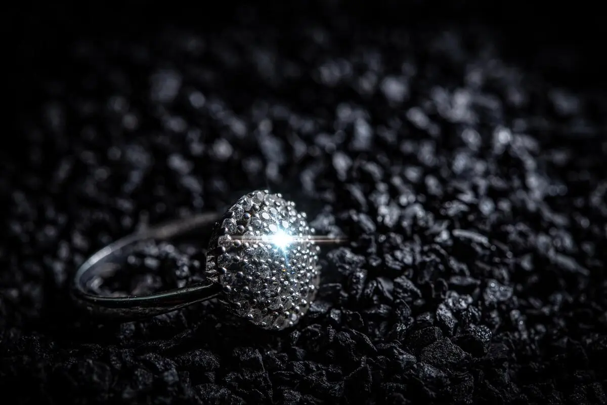 Meteorite ring resting on dark rocky material, showing metallic texture