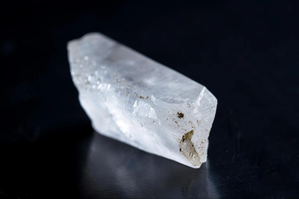 Cloudy quartz crystal point with natural inclusions on a dark surface