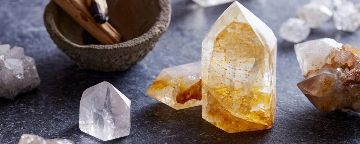 Citrine and clear quartz points arranged with palo santo sticks on dark slate