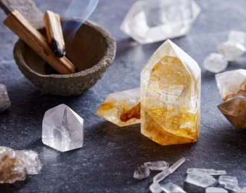 Citrine and clear quartz points arranged with palo santo sticks on dark slate