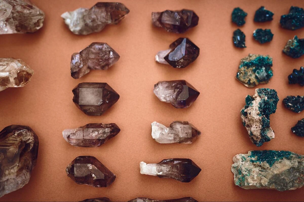 Wholesale Crystal Specimens Flat Lay Rows of smoky quartz points and green dioptase specimens laid out on a terracotta surface